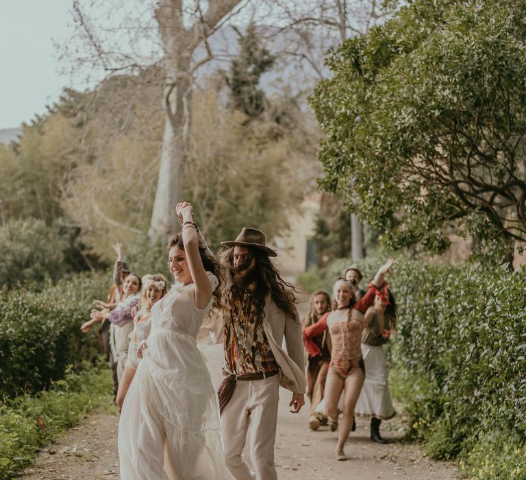 Groom twirls bride around on their wedding day as circus performers dance behind them 