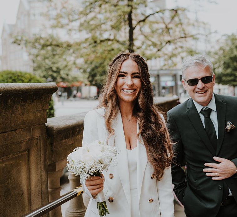 Beautiful bride with long wavy hair in a white blazer, camisole and trousers