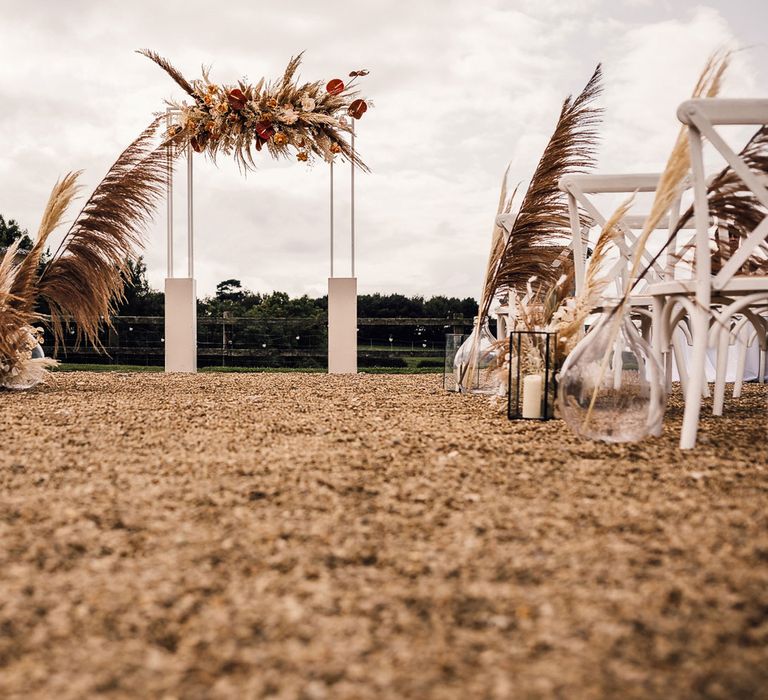 White rectangular wedding arch with rustic pampas grass cloud and pampas grass aisle decorations for outdoor wedding ceremony in Dorset