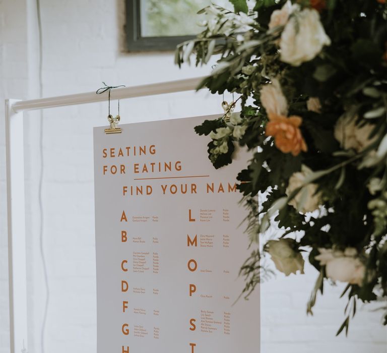 Seating for Eating contemporary wedding table plan with orange font 