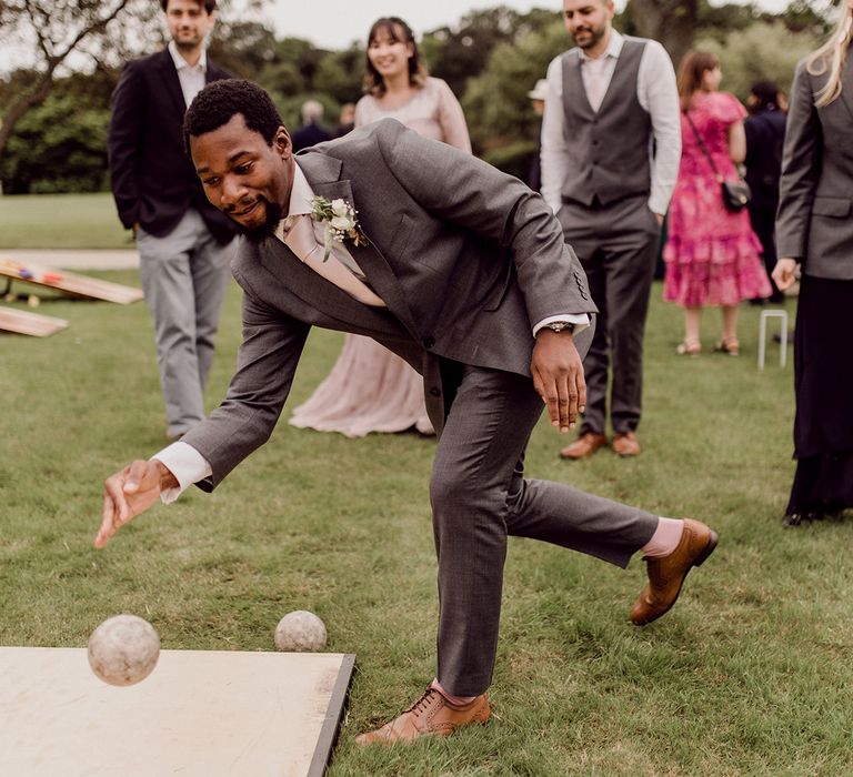 Wedding guest plays bowling outdoors  | Joshua Gooding Photography