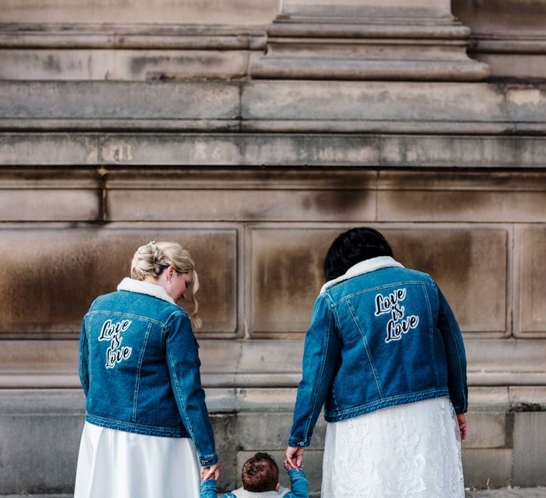 Two brides and their little boys in matching Love Is Love denim jackets 