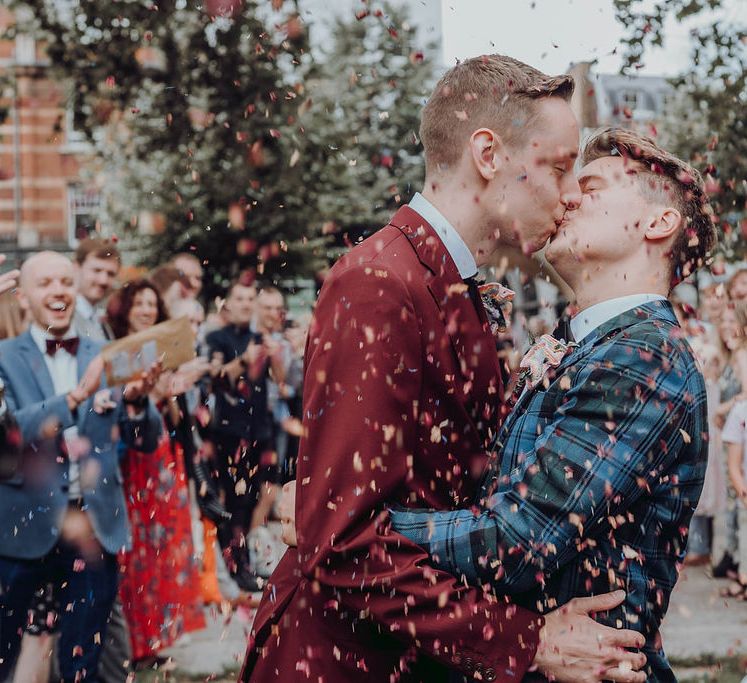 Grooms kiss as confetti is thrown around them on their wedding day | Kim Williams Weddings