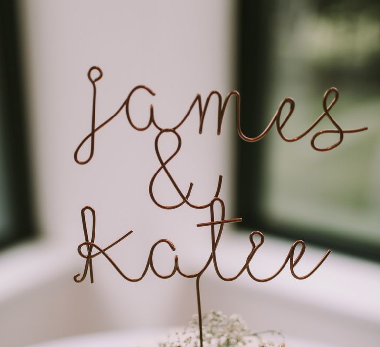 Simple wire wedding cake topper of the bride and grooms names 