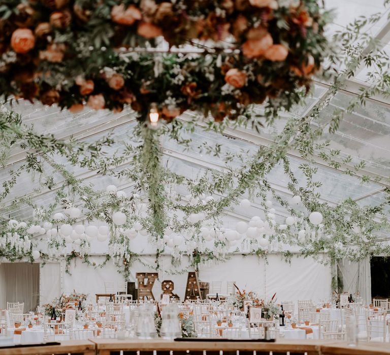 Interior of wedding reception marquee with clear roof, white ball lights and garlands for DIY garden wedding in Bedfordshire