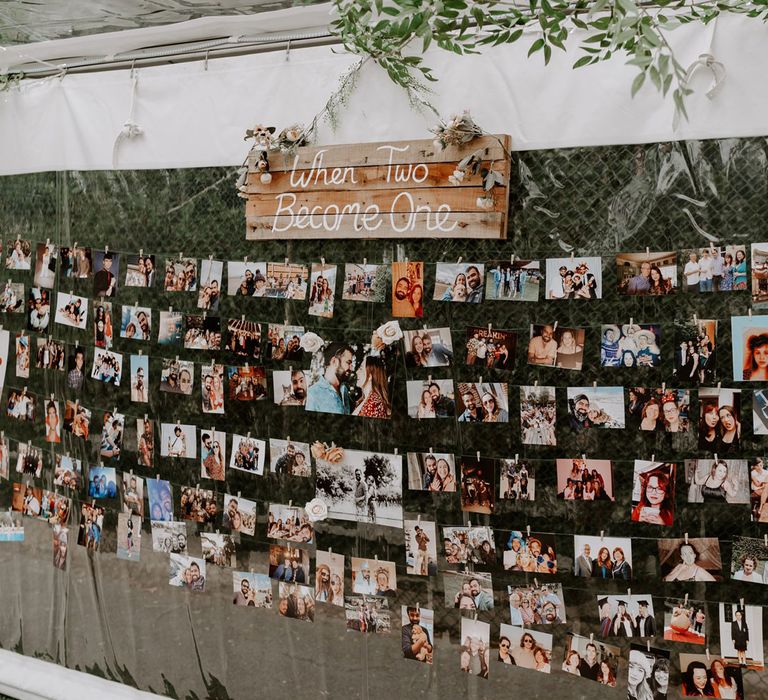 Various photos pegged to string across interior side of marquee with wooden wedding sign reading 'when two became one'