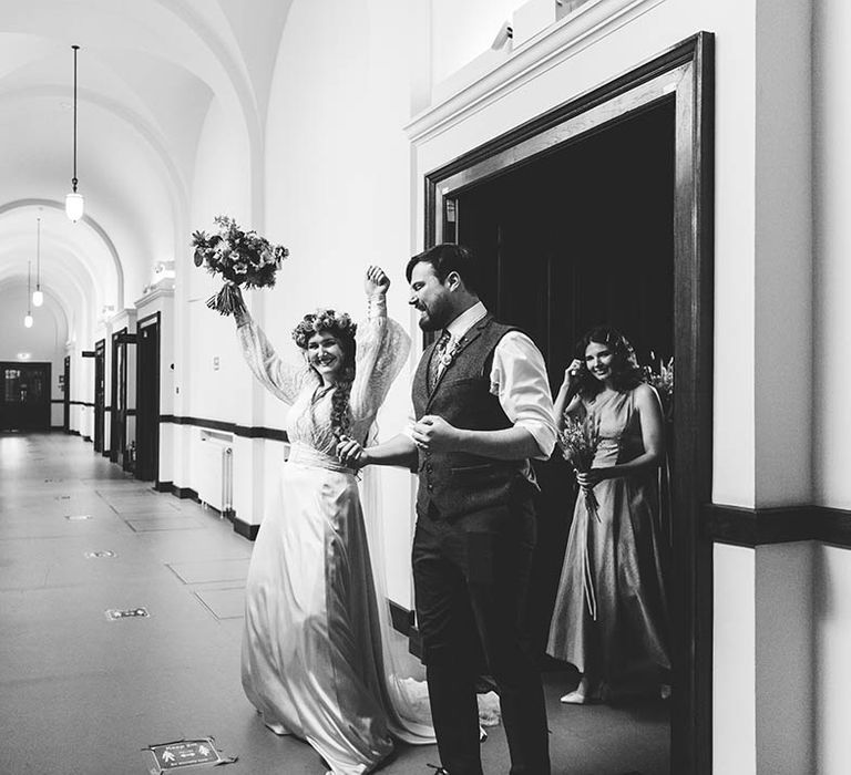 Bride celebrates as she stands by her husband in black & white image