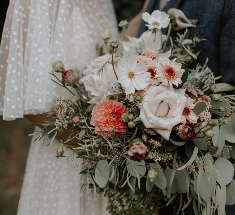 Bride holds floral bouquet complete with green foliage