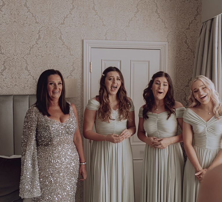 Bridesmaids wear pale green gowns as they see bride for the first time