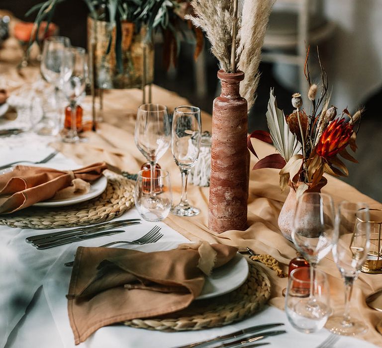 Boho chic tablescape complete with orange table runner and pampas grass decor 