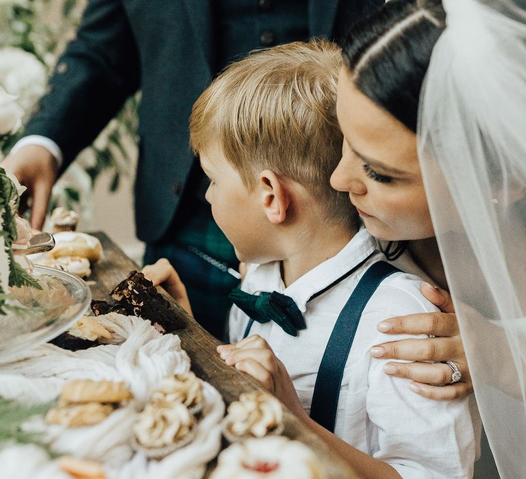 Bride, groom and son looking at the dessert table at their luxury English micro wedding 