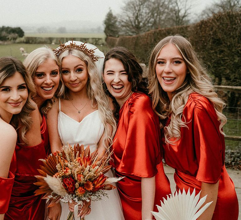 Bride in gold wedding crown with bridesmaid in orange satin dresses