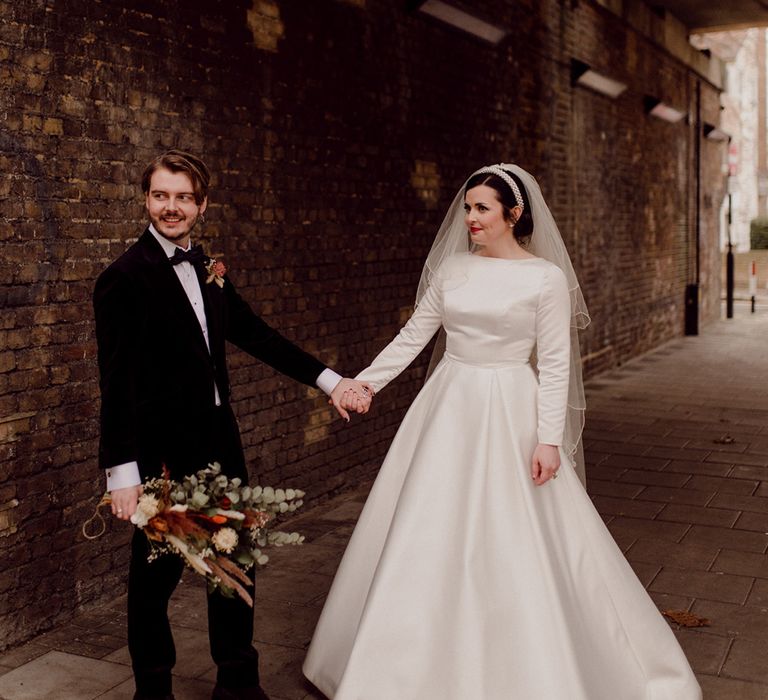 Bride and groom hold hands under the bridge 