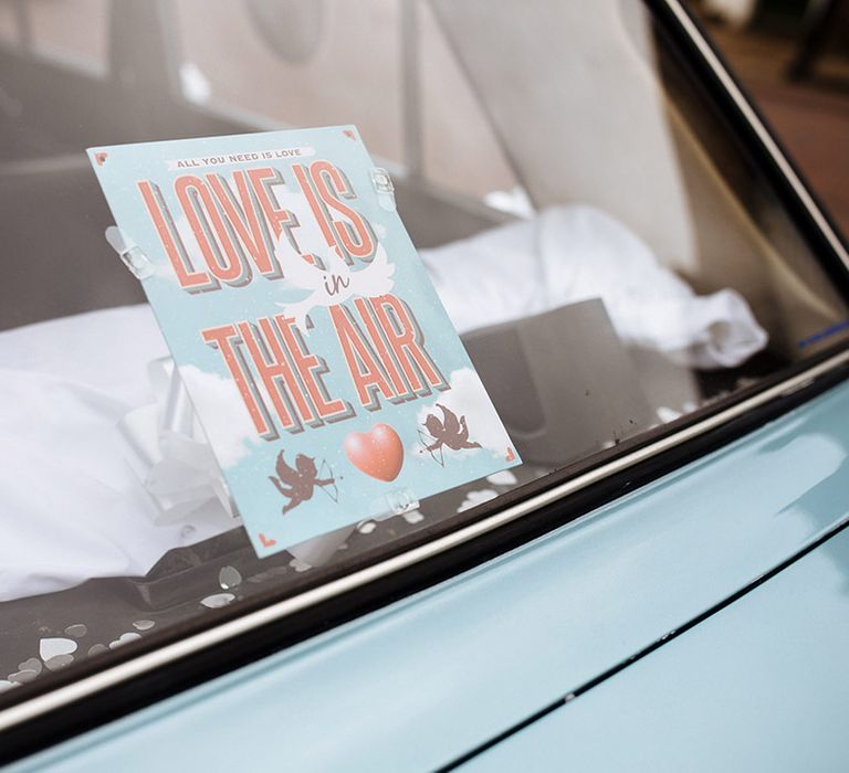 'Love is in the air' blue wedding sign with cupids and love hearts in baby blue vintage wedding car 