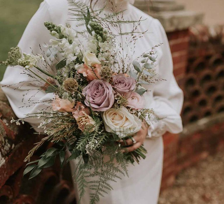 Bride holding mixed neutral bouquet with roses and dried flowers