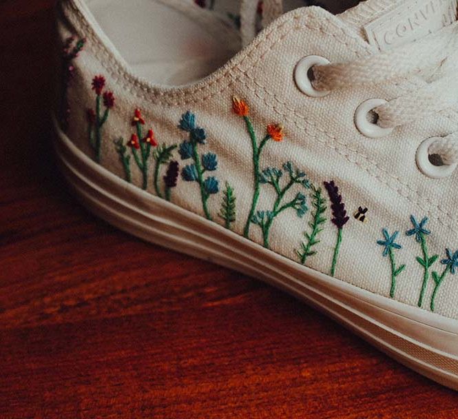 Bride wears custom white converses with colourful stitched flowers on the sides