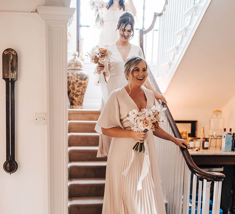 Bridesmaids in pale pink butterfly sleeve plated dresses with white block heels and neutral bouquets