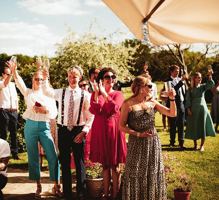 Wedding guests raise a toast for the newlyweds at home outdoor summer wedding 