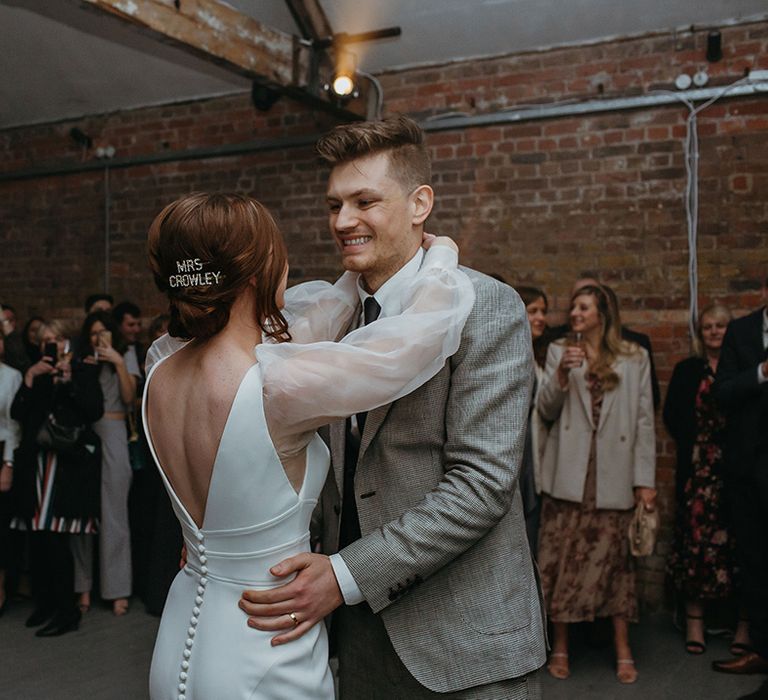 Bride and groom have their first dance with groom in Reiss suit and bride in button detail wedding dress and custom diamanté hair clips