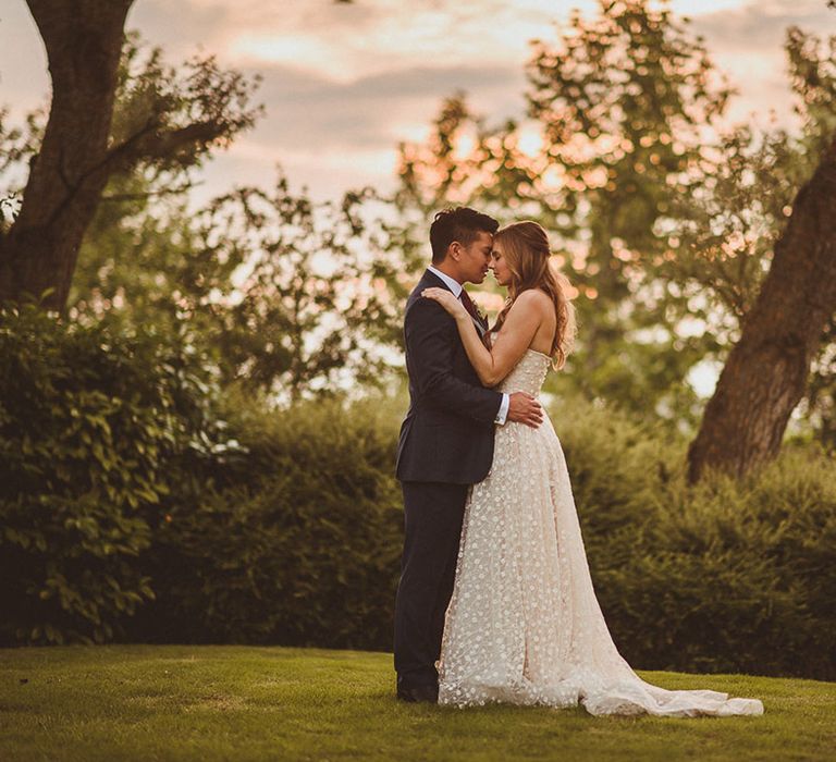 Bride and groom share an embrace and place their foreheads against each other 