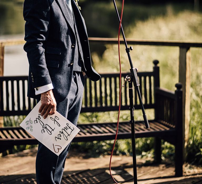 Father of the bride in blue suit and sunglasses reads out his wedding speech 