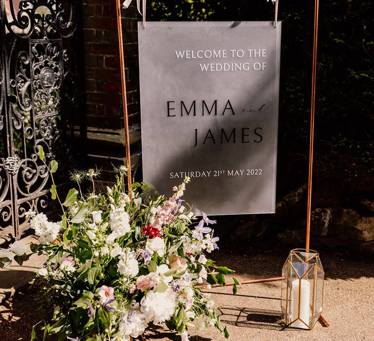 Frosted welcome wedding sign on copper frame with candle in geometric lantern and pink and white wedding flowers 