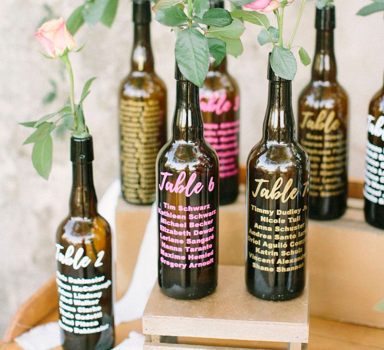 Repurposed alcohol bottles with colourful font seating chart idea 