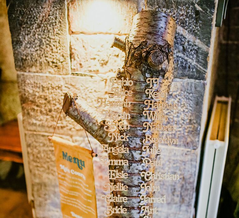 Tree trunk table plan complete with wooden names alongside hanging fabric menu banner 