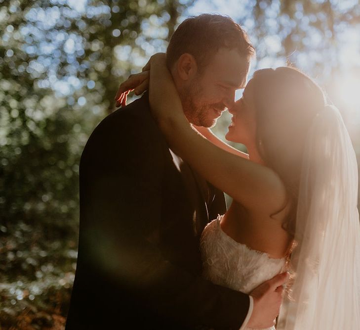 Bride & groom hold one another as the sun begins to set during golden hour couples portraits 