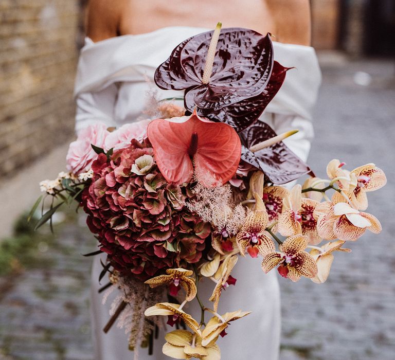 Bride holding a bouquet with anthuriums, hydrangeas, orchids and roses for city wedding 