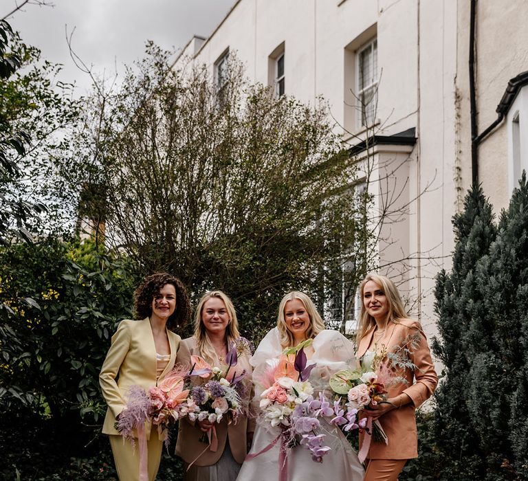 Bridesmaids wear yellow, brown and orange pastel coloured suits complete with white T-shirts for modern styled wedding 