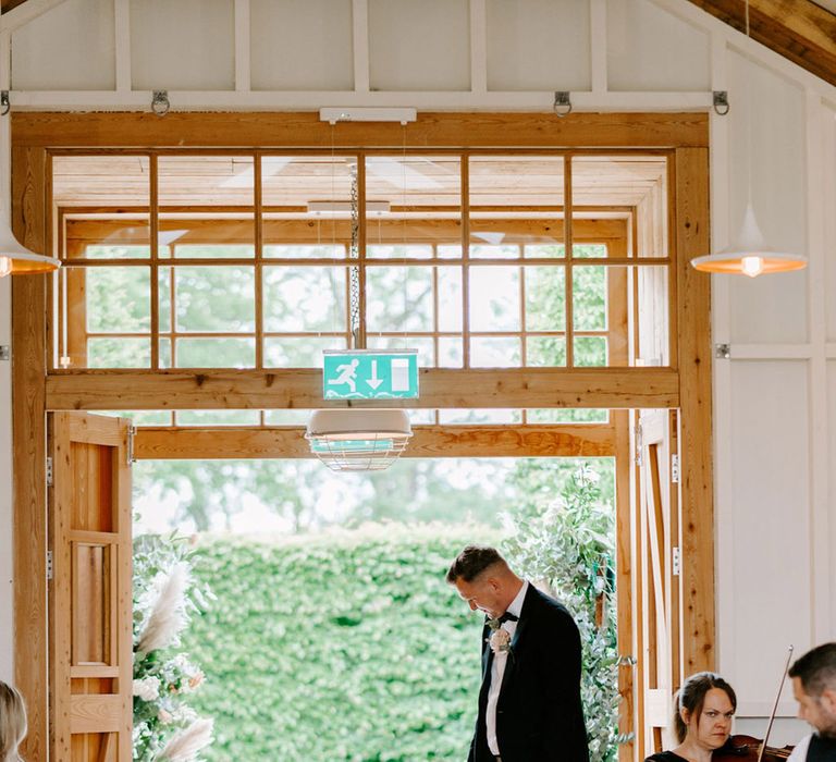 Two year old page boy walks down the aisle in black tie 