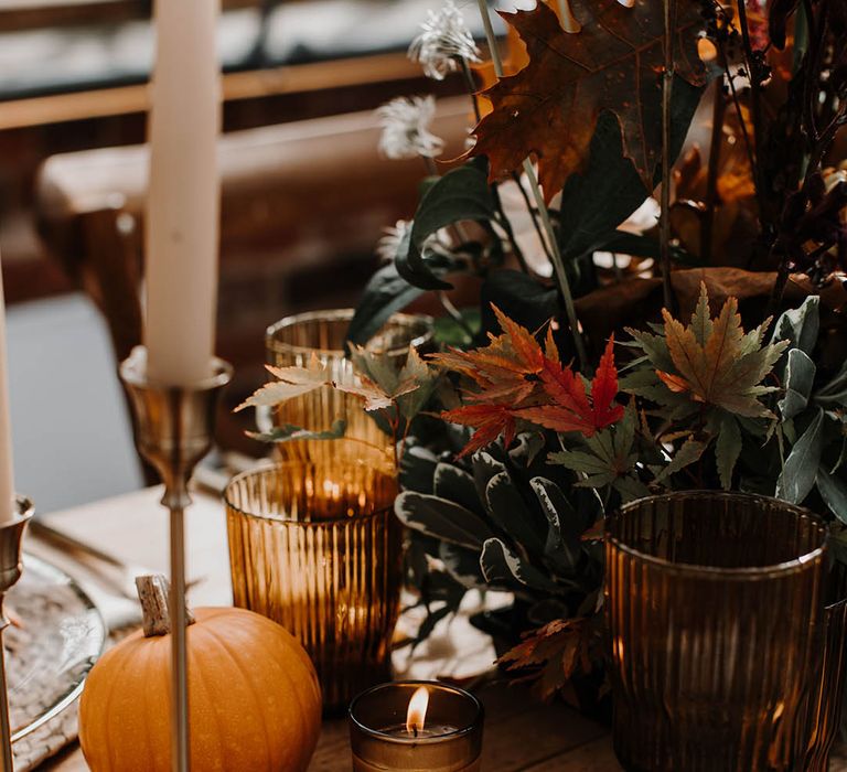 Mini pumpkins, dark florals, dark coloured glassware and white taper candles for the table centrepiece 