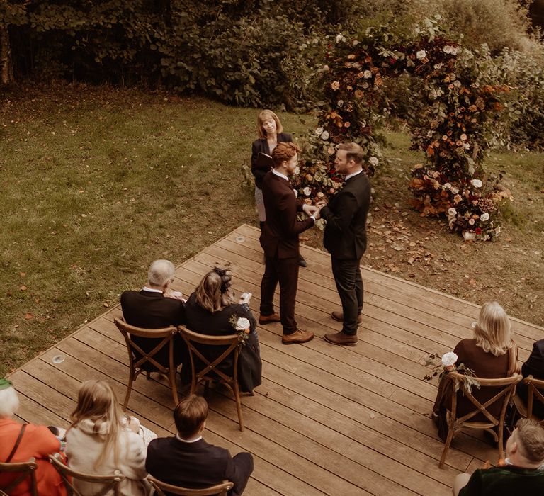 Grooms hold hands as they participate in their gay wedding ceremony 