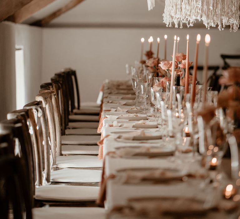 Soft pink and peach taper candles and flowers with white wedding drapery at Pennard House 