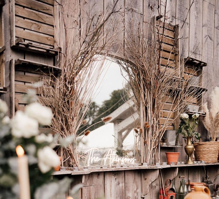 Outdoor mirror surrounded by branches and a customised neon sign with the couple's new last name