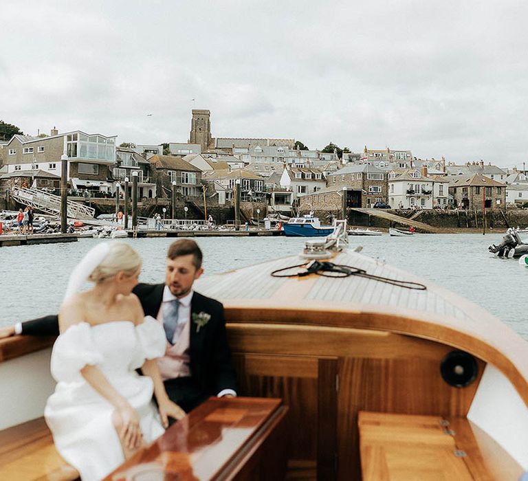 Bride & groom ride across the sea in boat during Salcombe wedding 