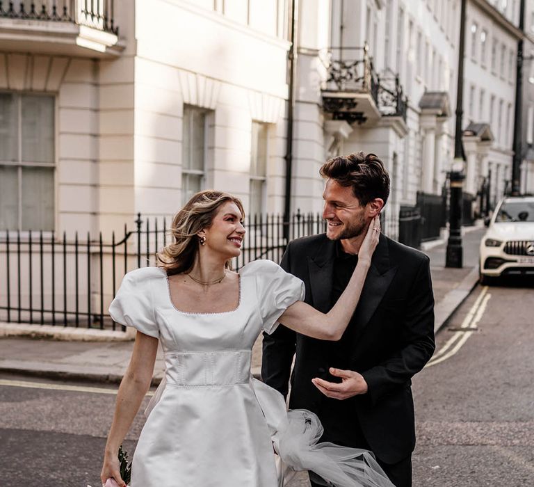 Bride in a short wedding dress with puffed sleeves and bow styling to the back complete with a square neckline 