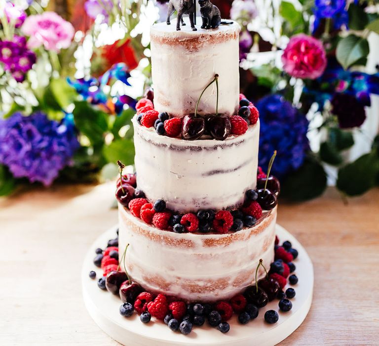 Three tiered buttercream wedding cake with laser cut personalised topper and animal wedding cake toppers with blueberry, cherry and raspberry decorations