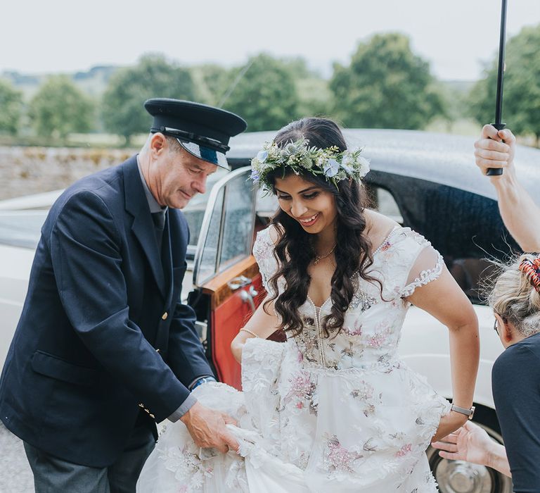 Bride in a floral Savin London Amelia Dress getting our of her classic wedding car