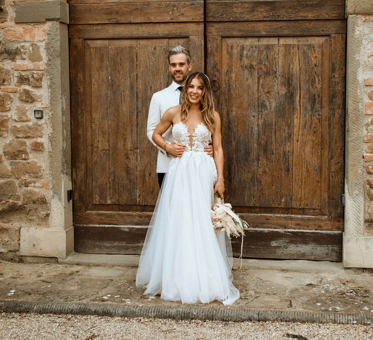 Couple portrait featuring bride in tulle embroidered plunge wedding dress and groom in relaxed linen wedding suit