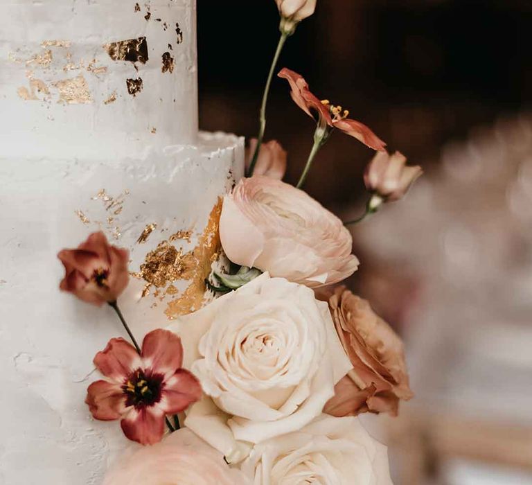 Iced buttercream wedding cake with dried pink flower cake decorations and gold flecks 