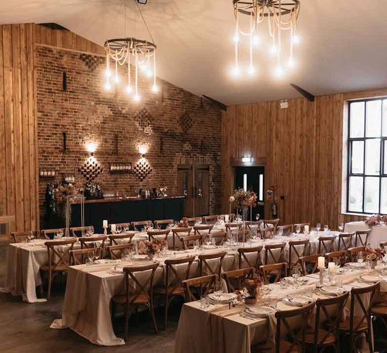 Reception room of Lodge Farm wedding venue Essex with rustic luxe wedding tablescapes and festoon lighting 