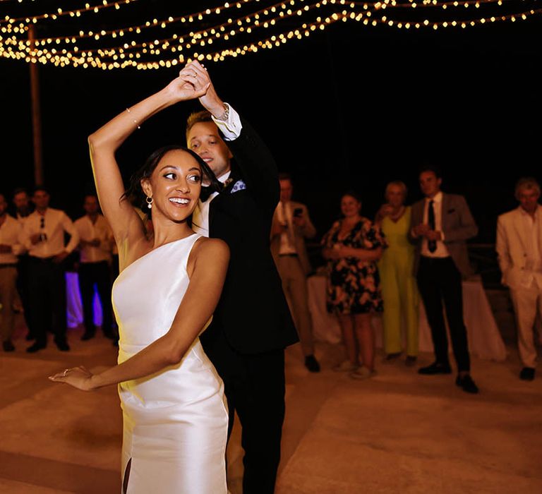 bride and groom first dance with bride in one shoulder wedding dress