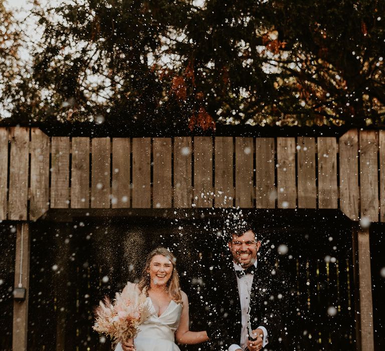 Bride and groom pop champagne at their wedding to celebrate the big day 