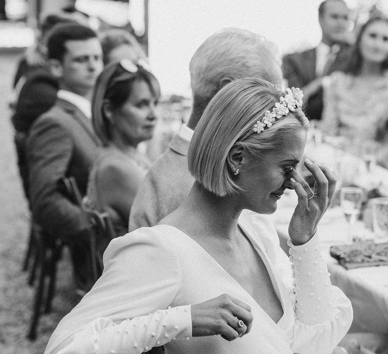 emotional bride in a flower headband and long sleeve wedding dress with pearl cuff embellishments 