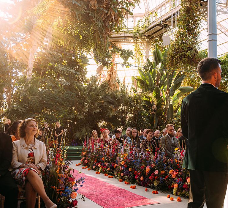 Sunny glasshouse wedding venue with the bride in a ruffle wedding dress and from in black tie at botanical theme wedding 