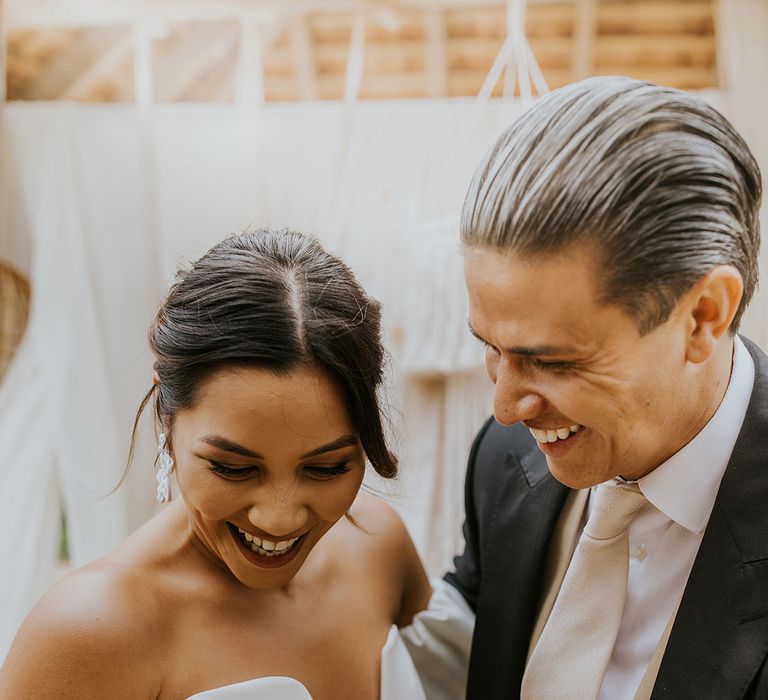 bride in a strapless wedding dress with puff sleeves laughing with her groom 