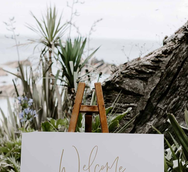 Minimalist white and gold wedding welcome sign at Tunnels Beaches 