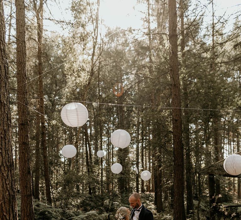 Camp Katur wedding venue in Yorkshire with white paper lanterns and fairy lights decorating the woodland ceremony space 